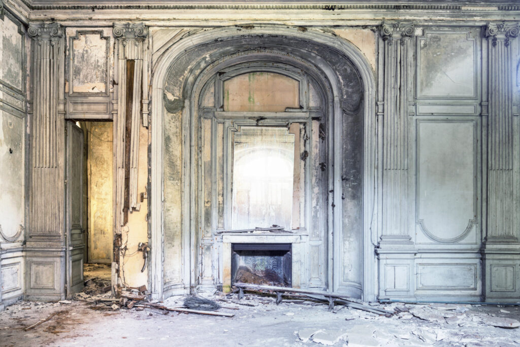 Salon d’un château français où cheminée, moulures, boiseries et lumière naturelle évoquent la richesse du lieu.
