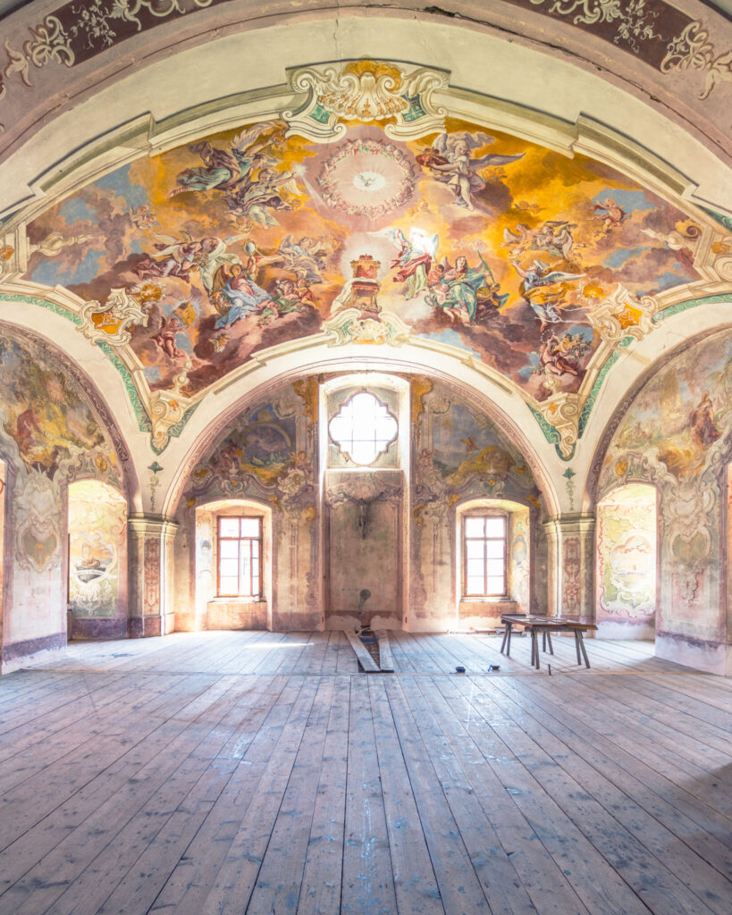 Galerie du cloître de Chotěšov traversée par une lumière douce révélant les volumes de l’ancien monastère.