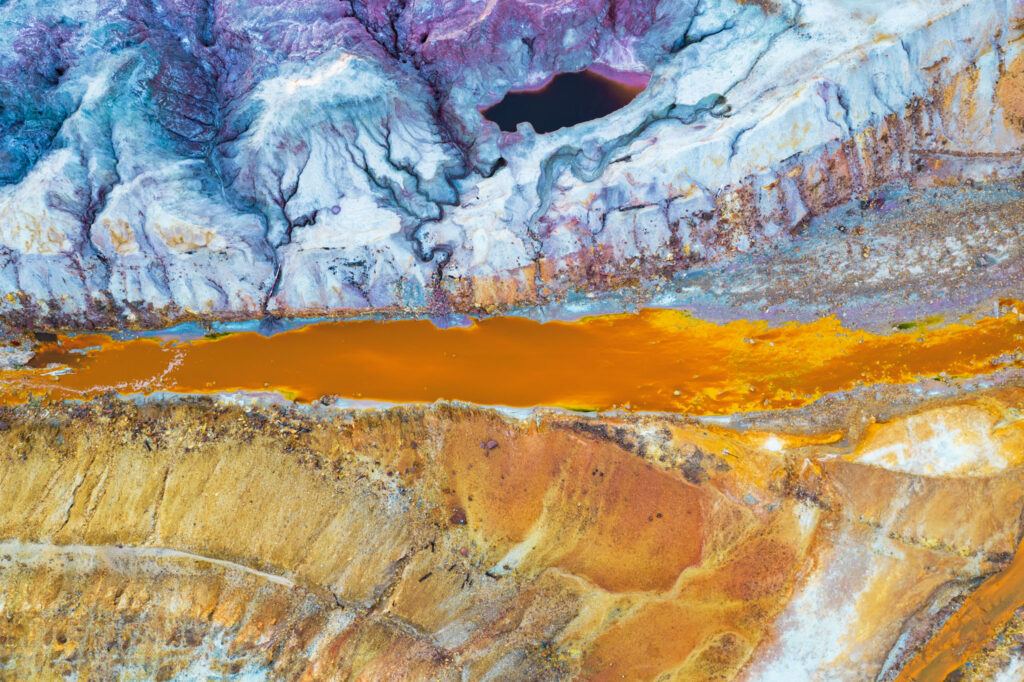 Vue aérienne zénithale d'une mine de cuivre abandonnée révélant des colorations minérales et des sédiments oxydés en Espagne.