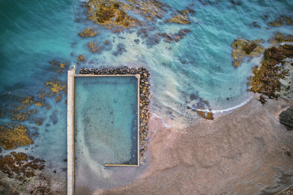 Vue zénithale d'une piscine côtière abandonnée et remplie par l'eau de l'océan Atlantique à Cancale en Bretagne.