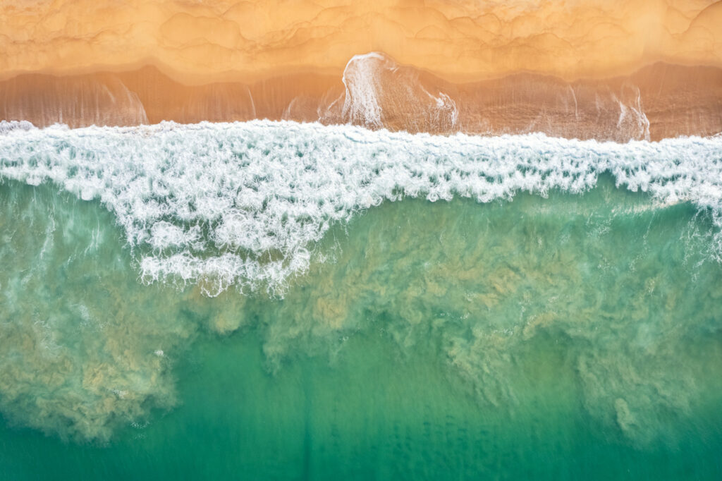 Rencontre de l'océan et du désert créant des mouvements d'écume et des nuages de sable aquatiques sur la côte de l'Angola.