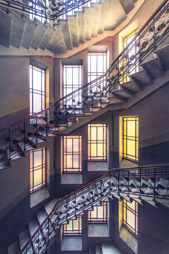 Cage d’escalier d’un immeuble historique de Milan avec rampe de style Liberty italien et architecture d’androne.