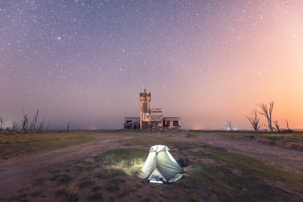 Tente éclairée de nuit dans le paysage désertique d’Epecuén, sous un ciel étoilé, en Argentine.