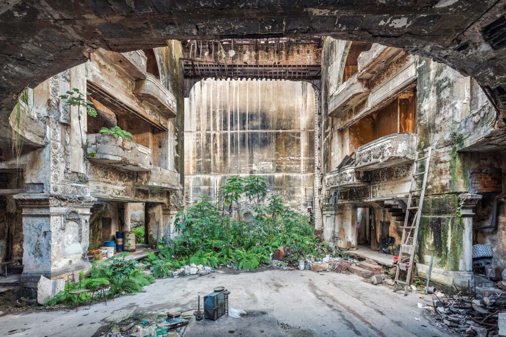 Intérieur abandonné du théâtre Campoamor à La Havane, avec balcons délabrés, végétation et architecture en ruine.