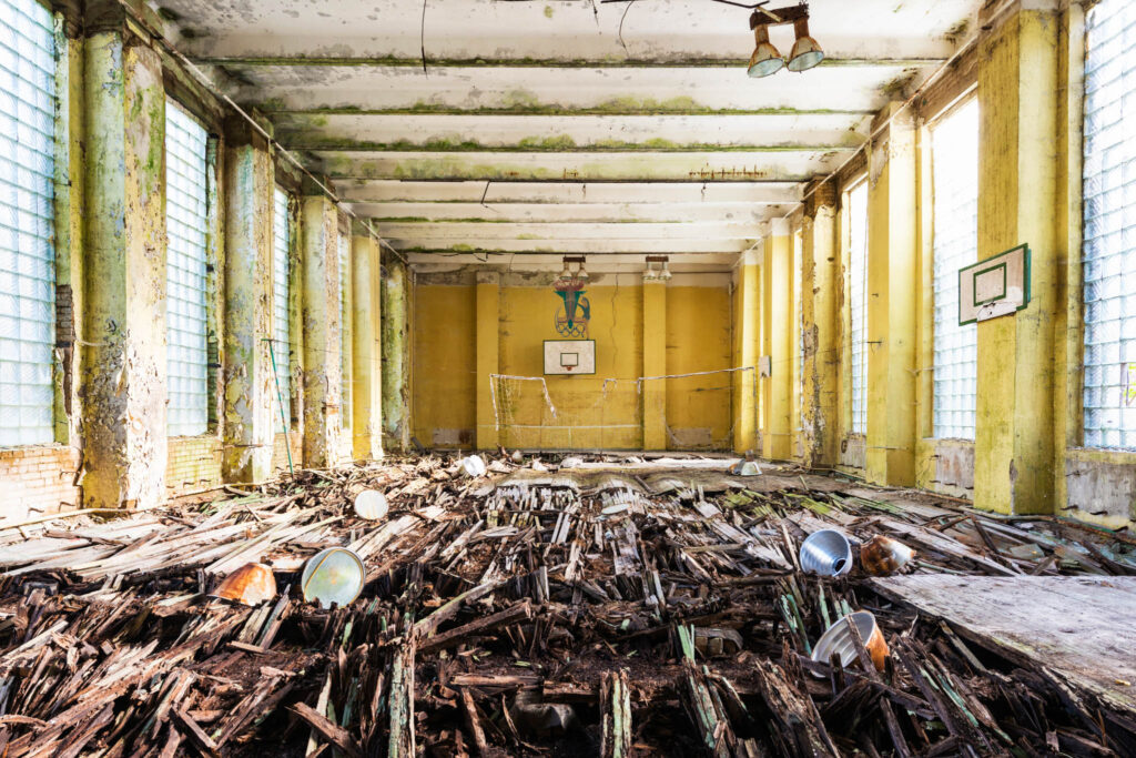 Salle abandonnée avec sol effondré et murs jaunes dans l’ancienne caserne de Krampnitz en Brandebourg.