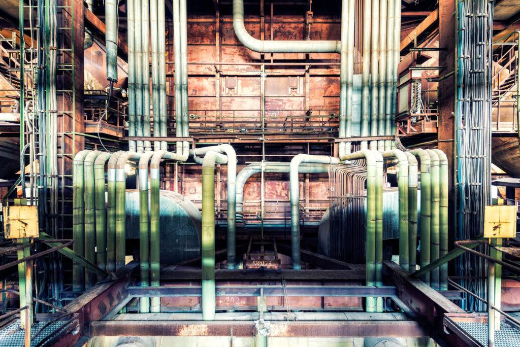 Réseau dense de chaudières, tuyaux et structures métalliques dans une ancienne centrale électrique.