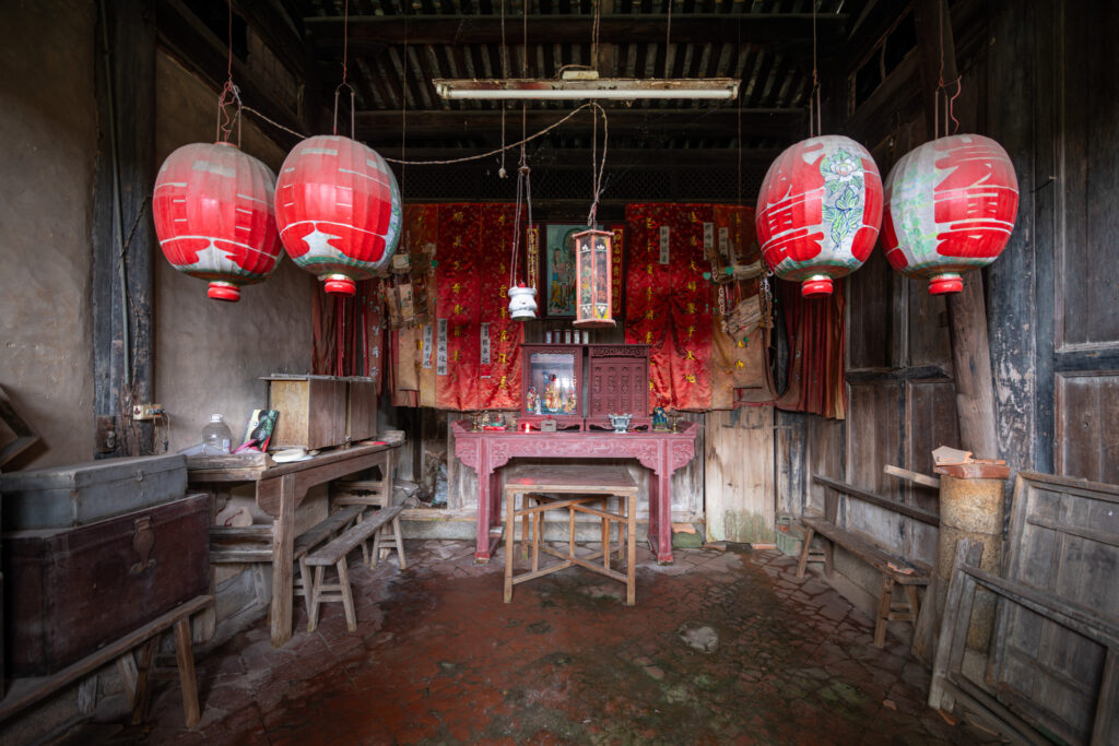 Autel ancestral dans une maison traditionnelle de Kinmen à Taïwan, avec lanternes rouges suspendues, boiseries sombres et mobilier rituel.