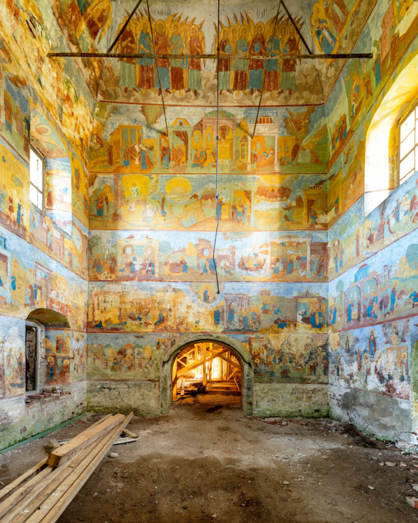 Mur couvert de plusieurs registres de peintures bibliques dans l’église de la Trinité de Krasnoye-Sumarokovo, autour d’une ouverture voûtée