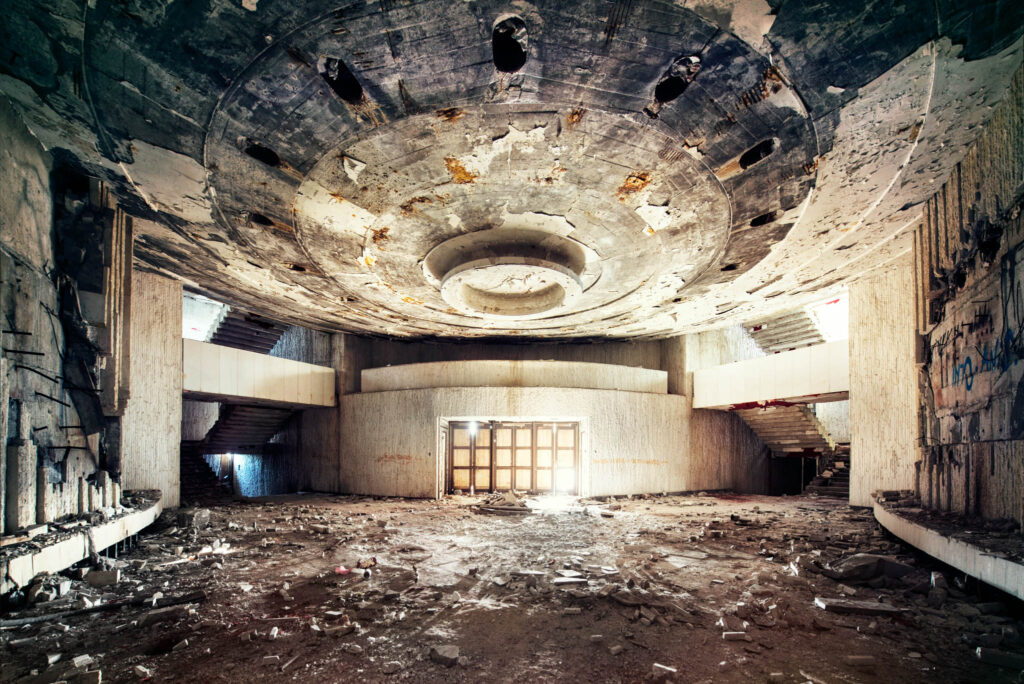 Hall abandonné du monument de Bouzloudja en Bulgarie, ancienne maison du Parti communiste bulgare, avec plafond circulaire dégradé et sol couvert de débris.
