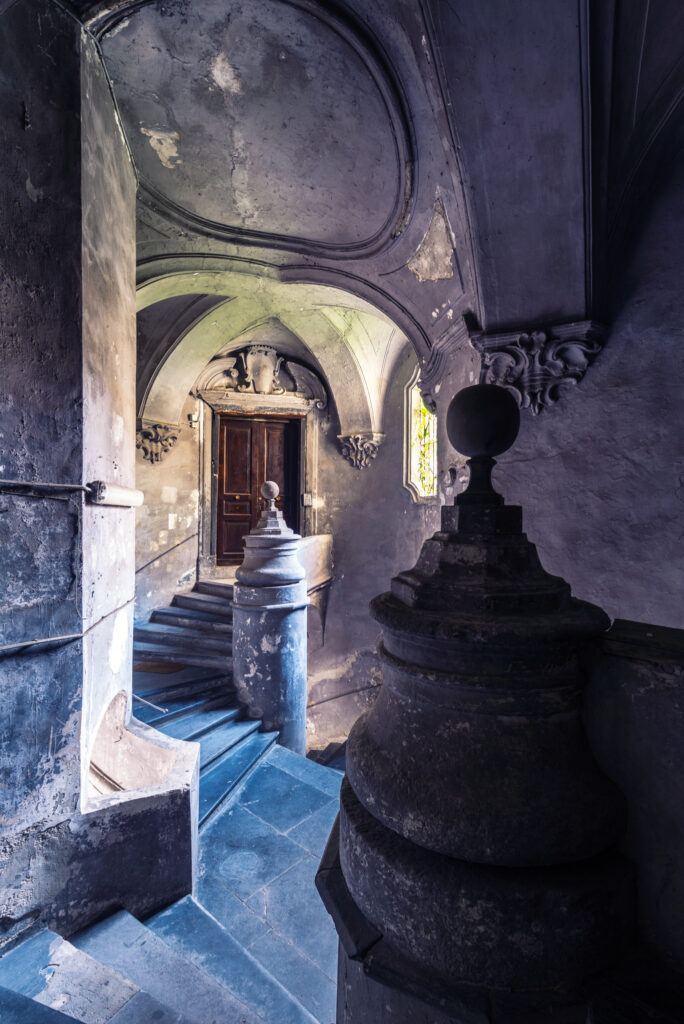 Escalier monumental du Palazzo San Felice à Naples, photographié dans une lumière sombre révélant son architecture baroque.