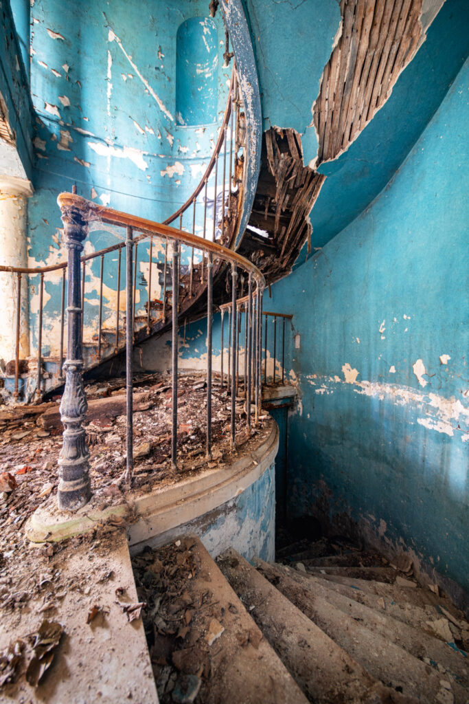 Cage d’escalier aux murs bleus dans un ancien château de la région Centre, photographiée avant sa rénovation.