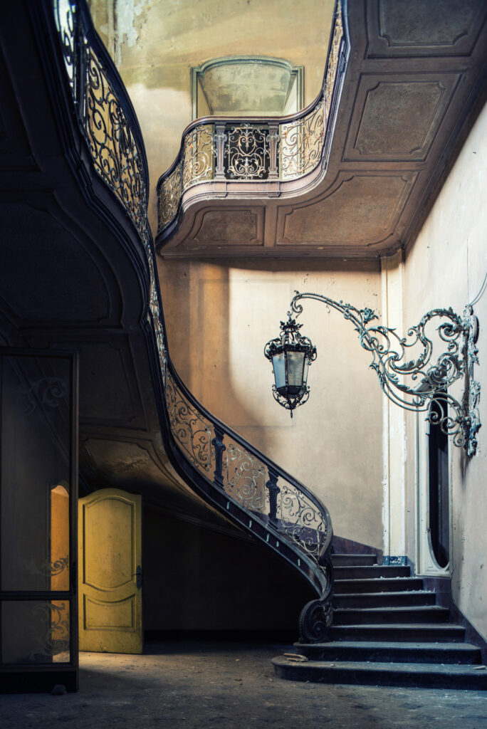 Grand escalier d’honneur de la Villa Borromeo d’Adda en Italie avec rampe ouvragée et ancienne lanterne suspendue.
