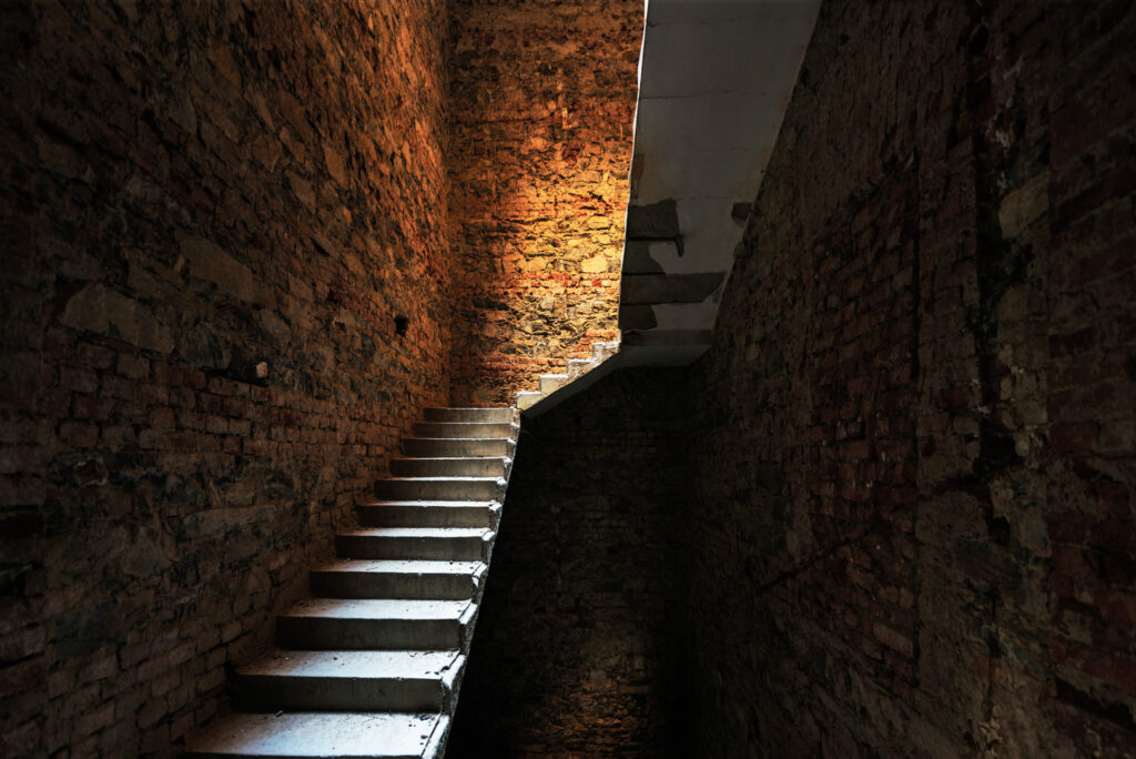 Escalier minimal en béton dans un chantier abandonné roumain, révélé par une lumière verticale traversant l’espace.