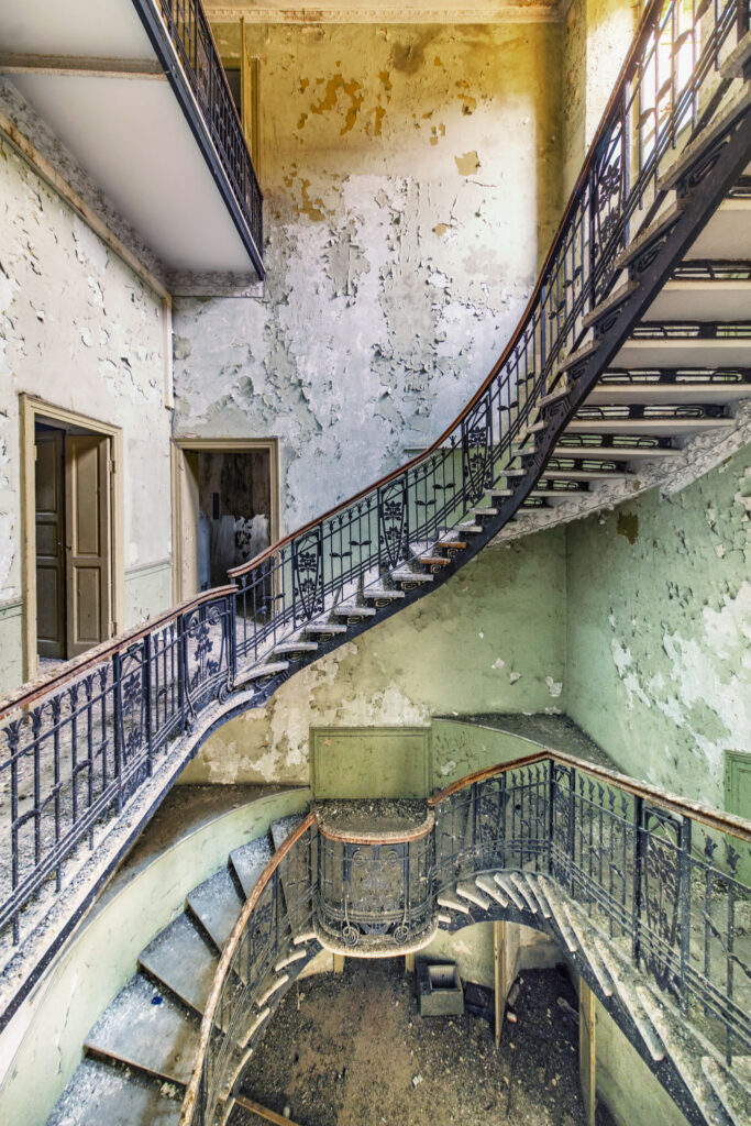 Escalier monumental de style Liberty dans une ancienne banque italienne, avec garde-corps métallique et architecture du début du XXe siècle.