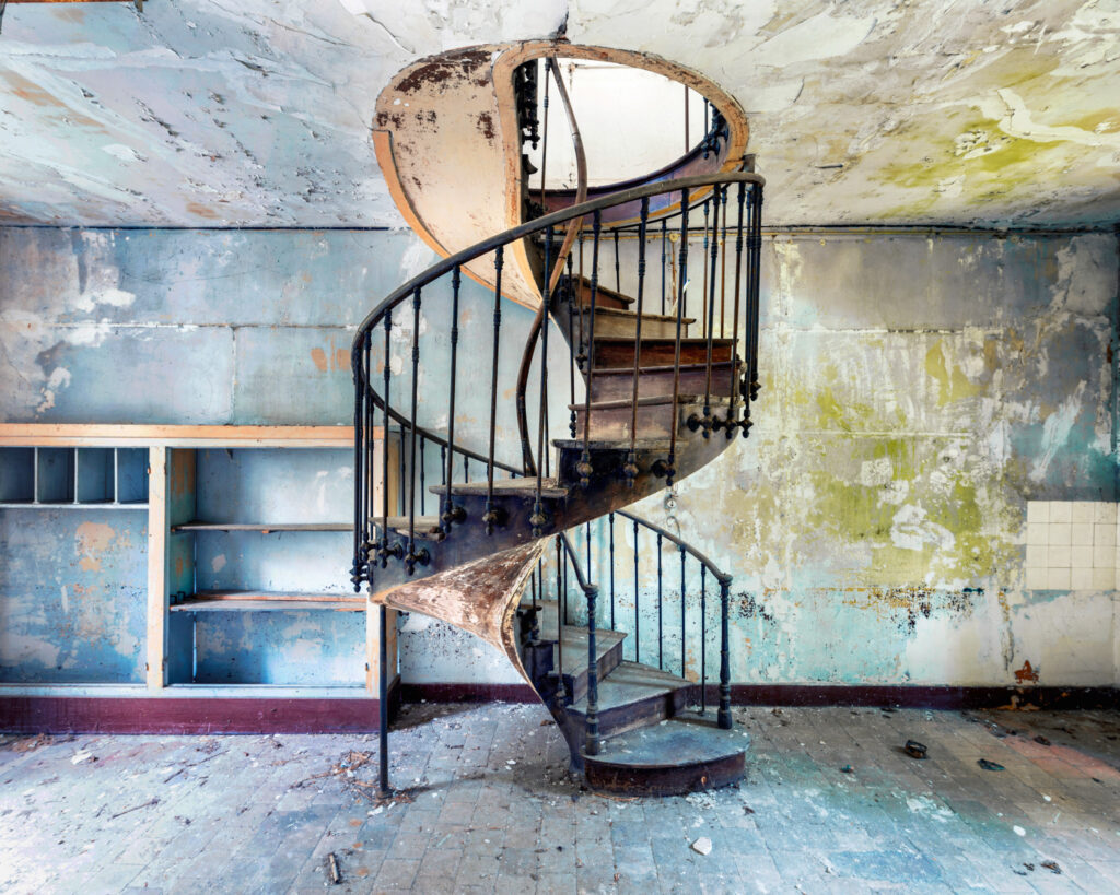 Escalier à colimaçon dans une ancienne salle d’archives aux murs bleu pastel d’un hôpital militaire.