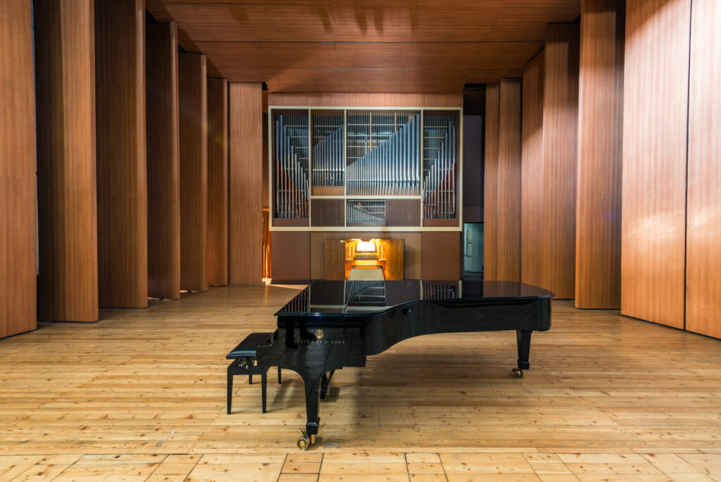 Salle de concert en bois du Conservatoire Vano Sarajishvili avec piano à queue et orgue en fond de scène.