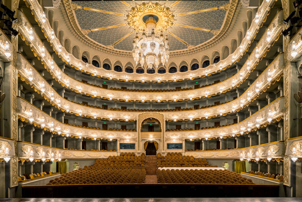 Grande salle dorée du Tbilisi Opera and Ballet State Theatre avec balcons, lustre et scène centrale.