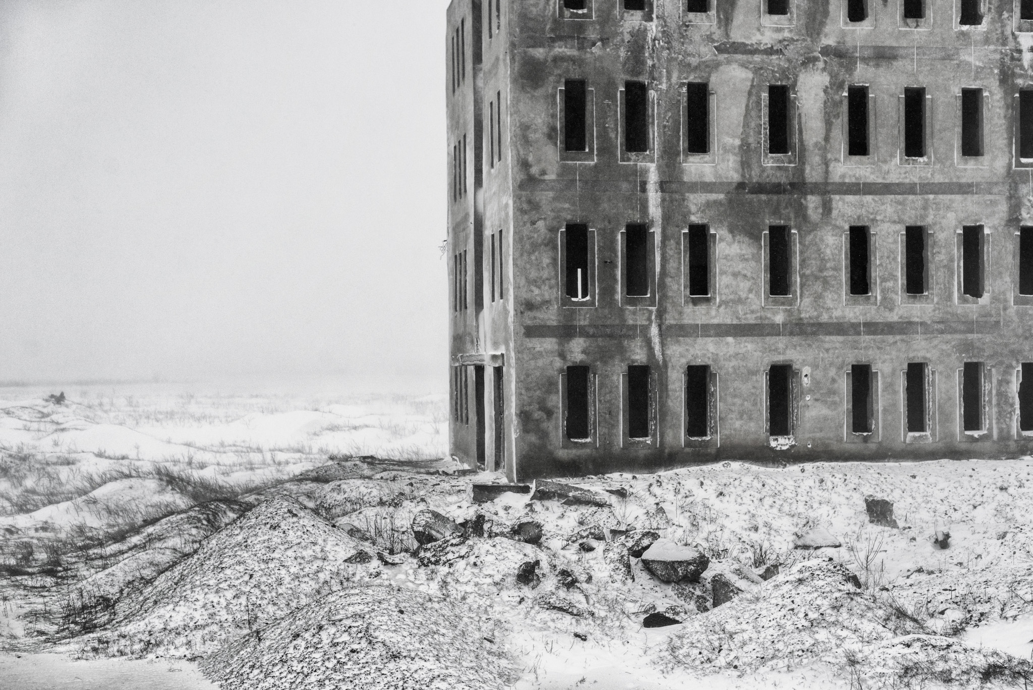 Bâtiment abandonné en béton occupant la droite d’un vaste paysage enneigé en Roumanie
