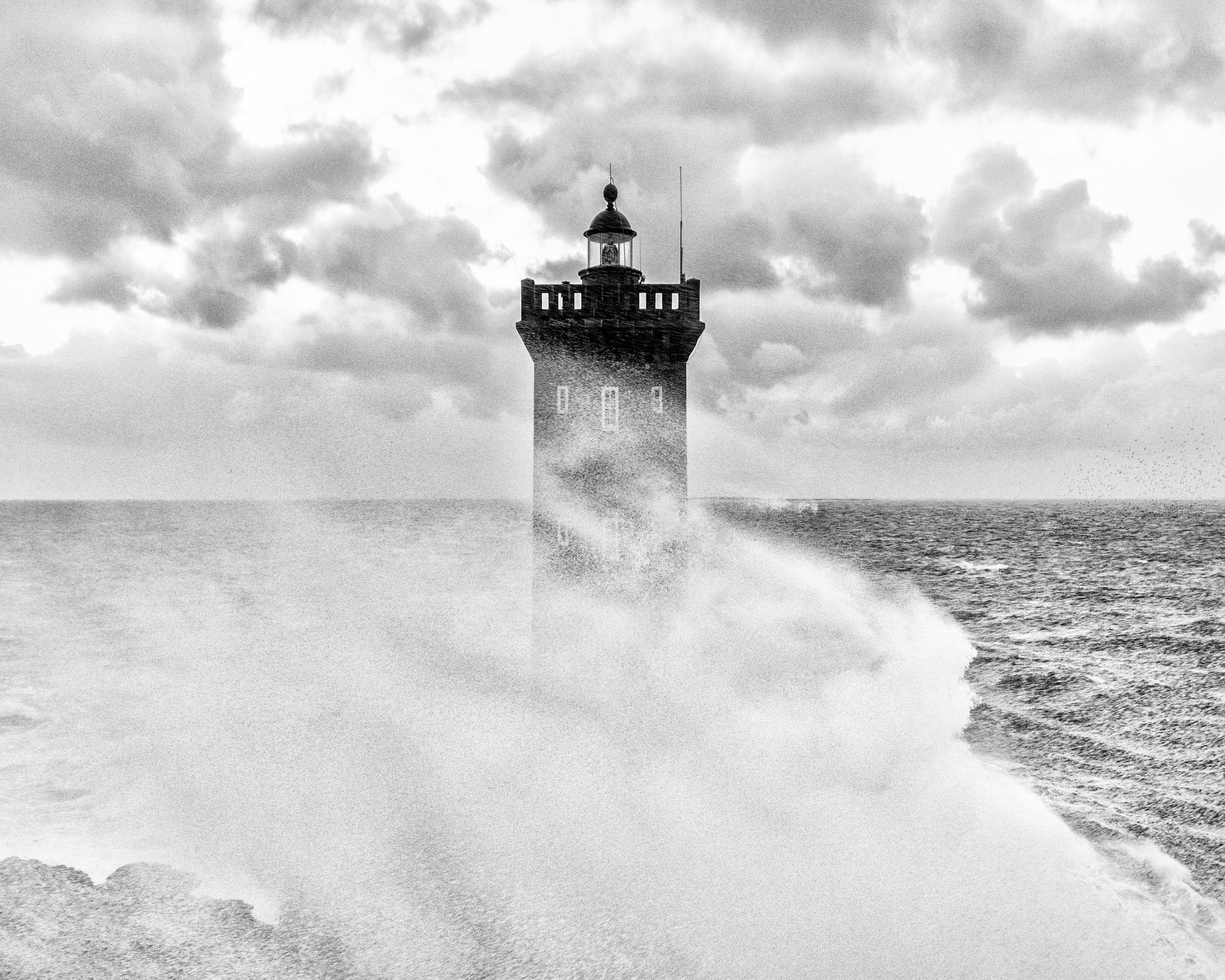 Énorme vague et écume masquant partiellement le phare de Kermorvan pendant la tempête Bella