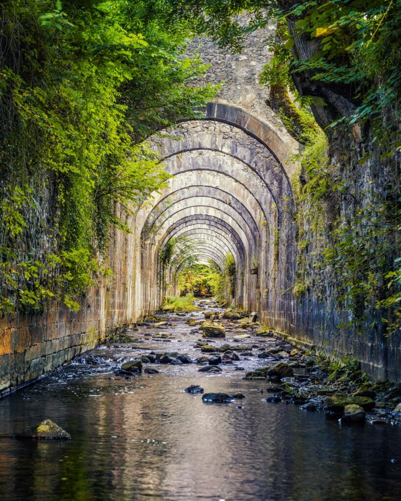 Succession d’arches en pierre de l’ancienne manufacture royale d’armes d’Orbaizeta au-dessus du río Legartza, avec murs couverts de mousse