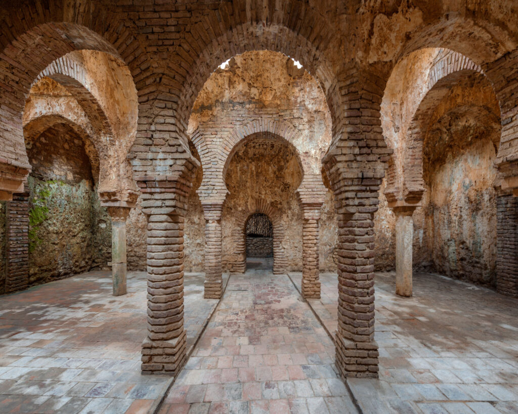 Intérieur des bains arabes de Ronda avec arcs outrepassés en brique et pierre, colonnes et voûtes percées de lucarnes étoilées