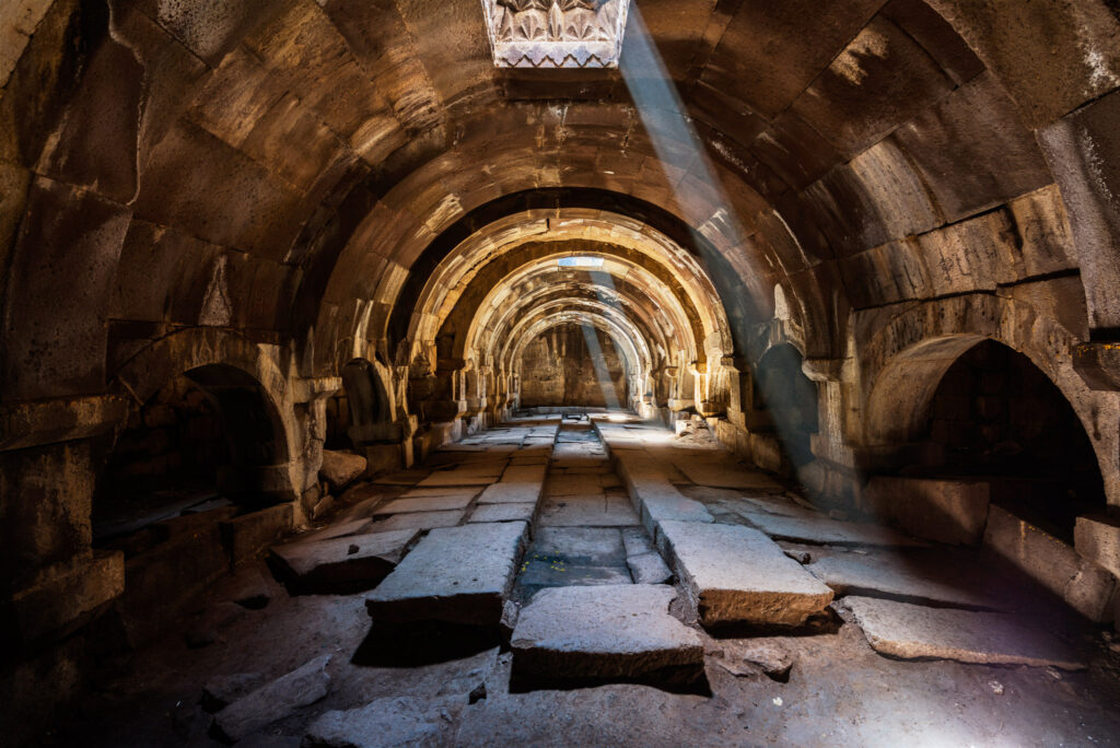 Longue salle voûtée du caravansérail médiéval de Selim en Arménie, construite en basalte et éclairée par des ouvertures zénithales