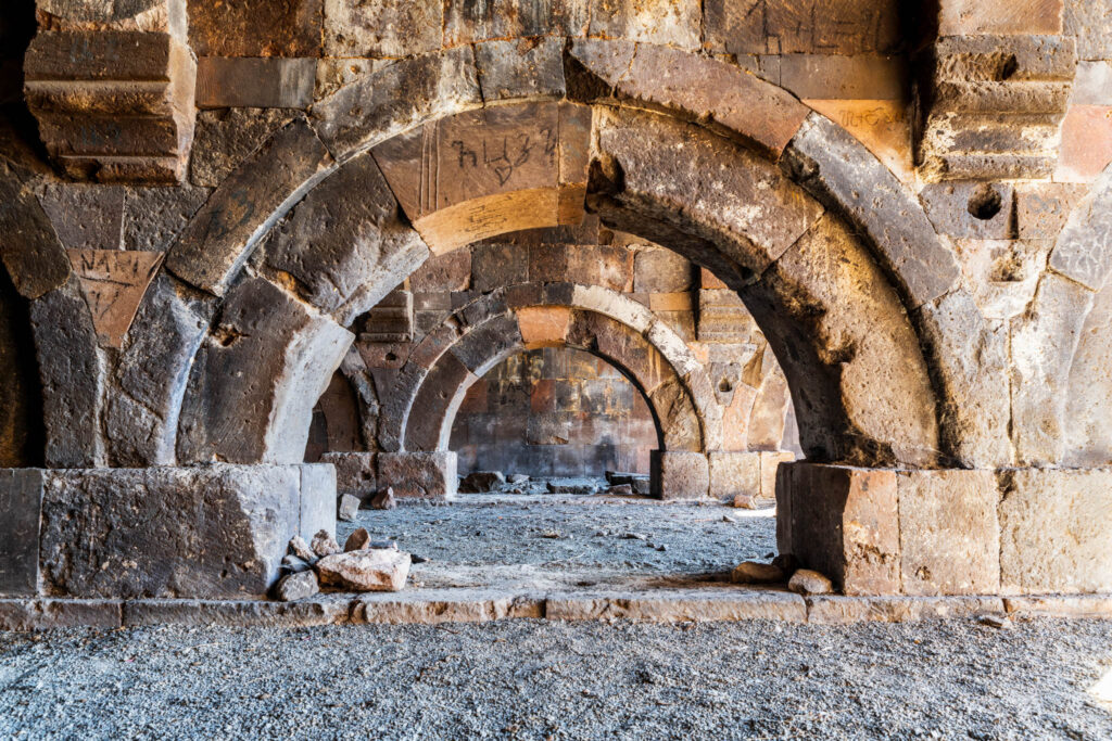 Succession d’arches médiévales construites en blocs de tuf volcanique noir dans un caravansérail en ruine en Arménie