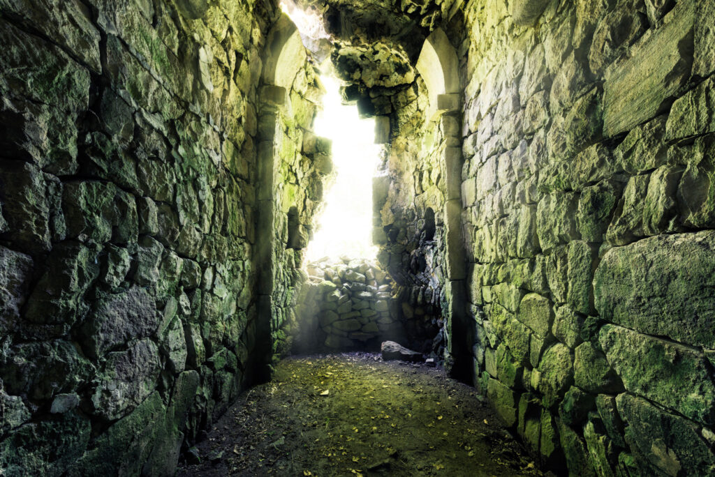 Pièce effondrée du monastère médiéval de Matosavank avec murs de pierre sombre, mousse et ouverture lumineuse sur la forêt arménienne