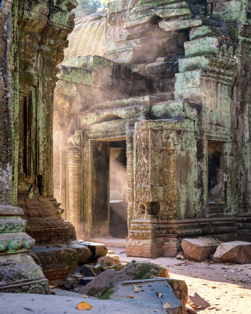 Rayons du soleil levant traversant une poussière en suspension dans les galeries de pierre du temple khmer de Ta Prohm