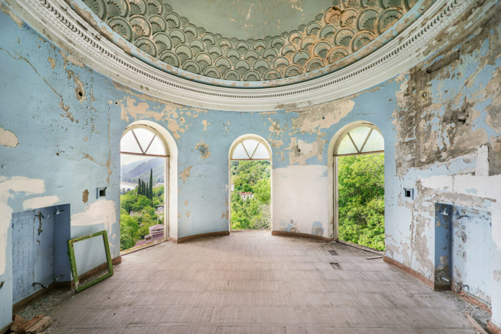 Salle circulaire bleu pâle d’un sanatorium abandonné de Gagra, ouverte par de grandes baies sur les montagnes et la mer Noire