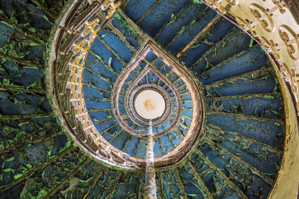 Vue zénithale d’un escalier en spirale dans la tour d’un château polonais, révélant sa géométrie architecturale.